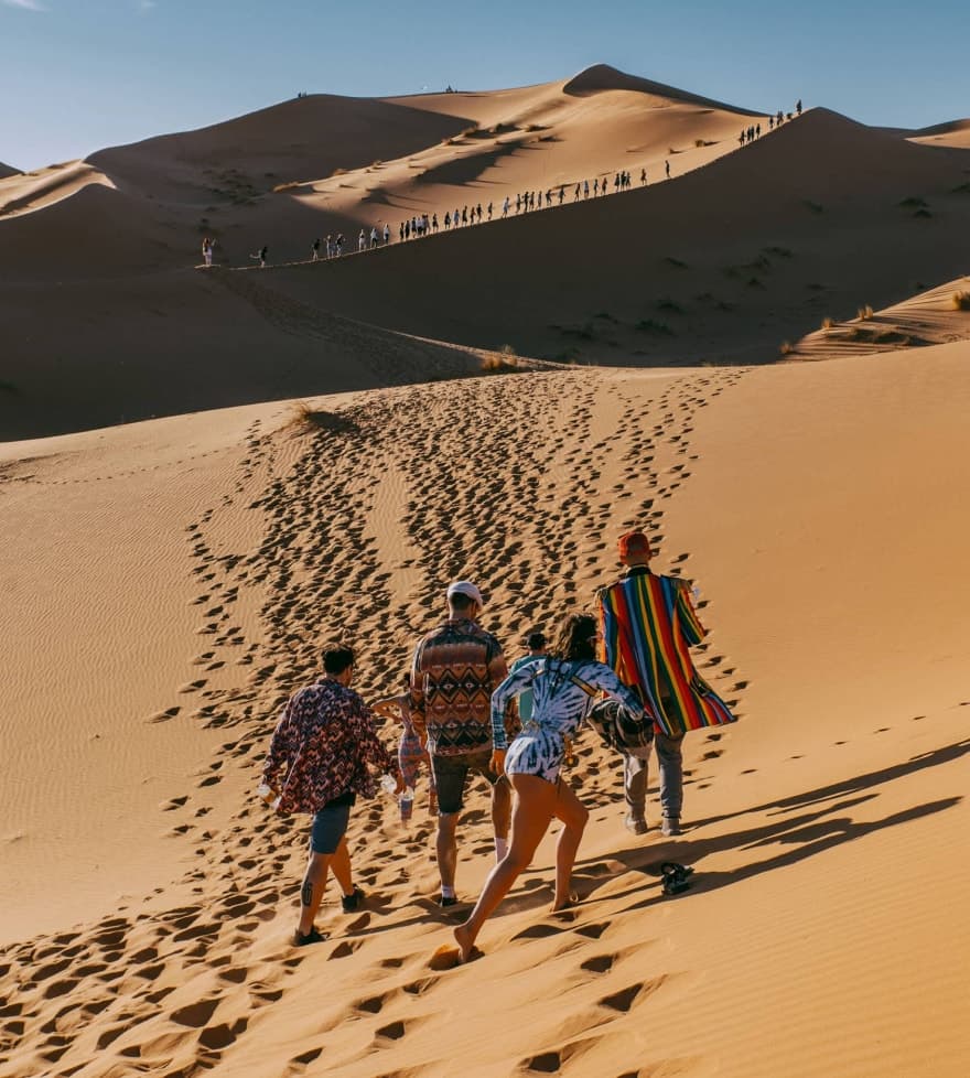 a group of people climbing a dune