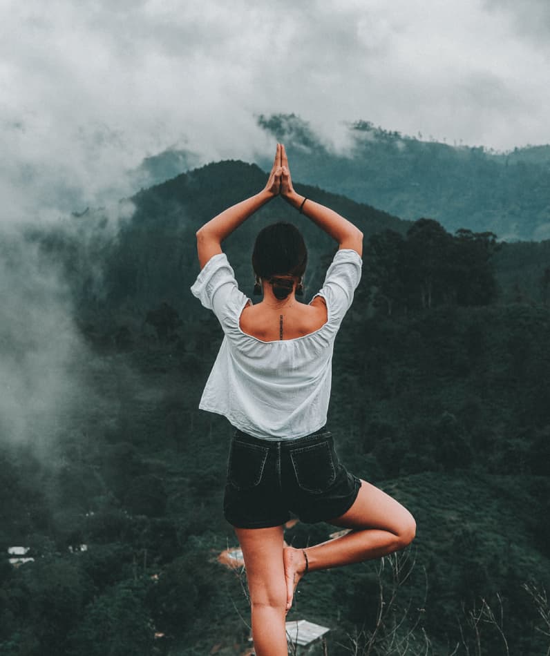 A woman does yoga on a mountaintop